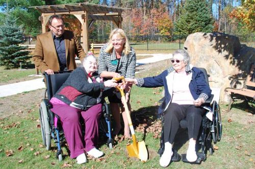 Residents Jessie Cox (front right) and Barb Ellsworth (front left) sink a golden shovel in the ground as Pine Meadow Administrator Bonnie George and building commiteee chair Ernest Lapchinski look on.